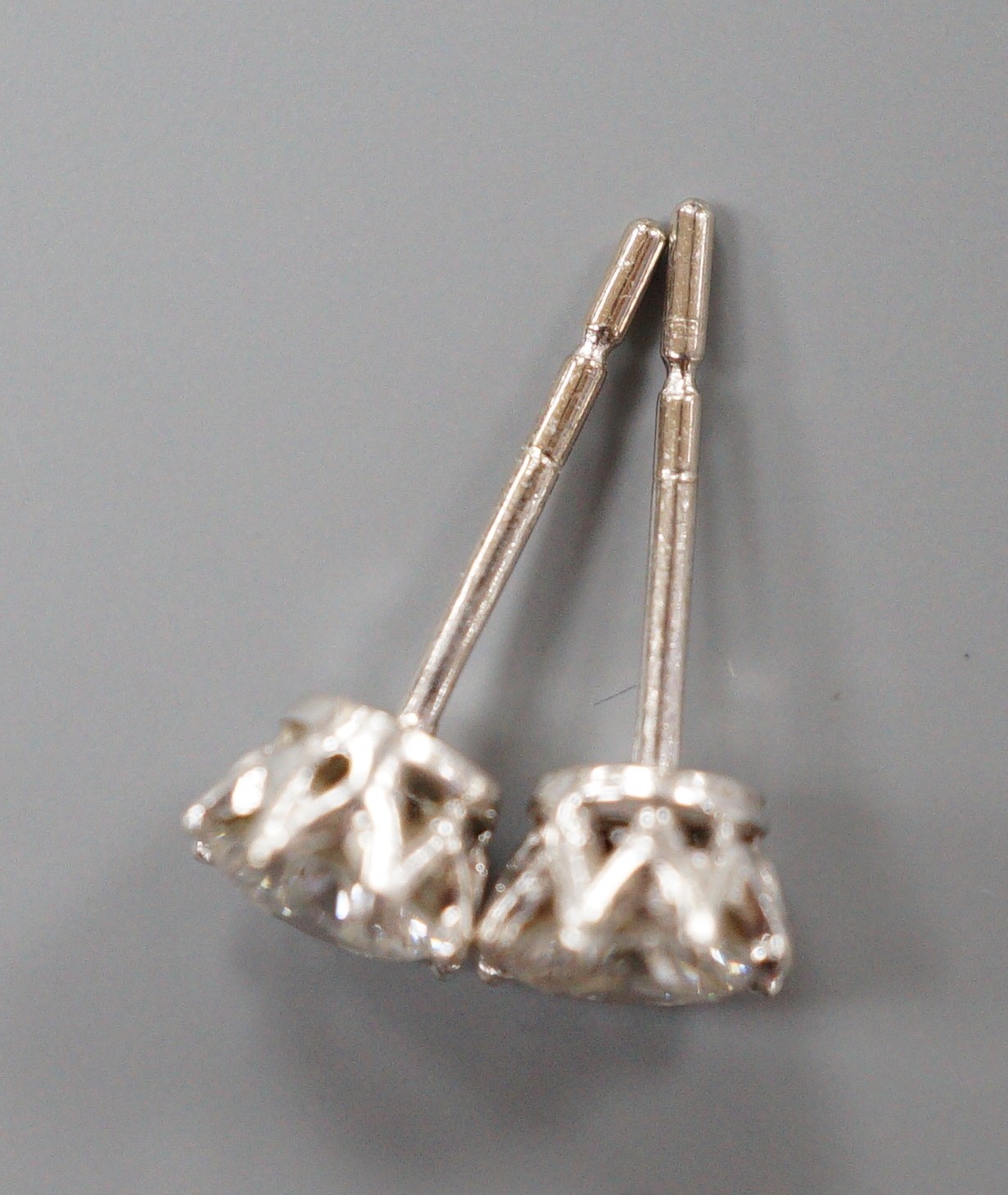 A modern pair of 18k white metal and solitaire diamond set ear studs (butterflies differ), gross weight 1.4 grams
